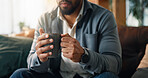 Coffee, hands and man on sofa in home with calm, peace or morning break with warm beverage. Espresso, relax and male person drinking cappuccino, latte or tea for wellness in living room at apartment.