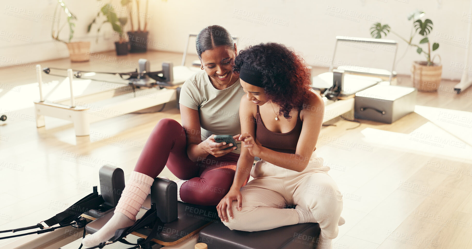 Buy stock photo Fitness, phone and smile with women in pilates class for break, conversation or social media. App, exercise and machine with happy friends on floor of studio for mobile health tracking or update