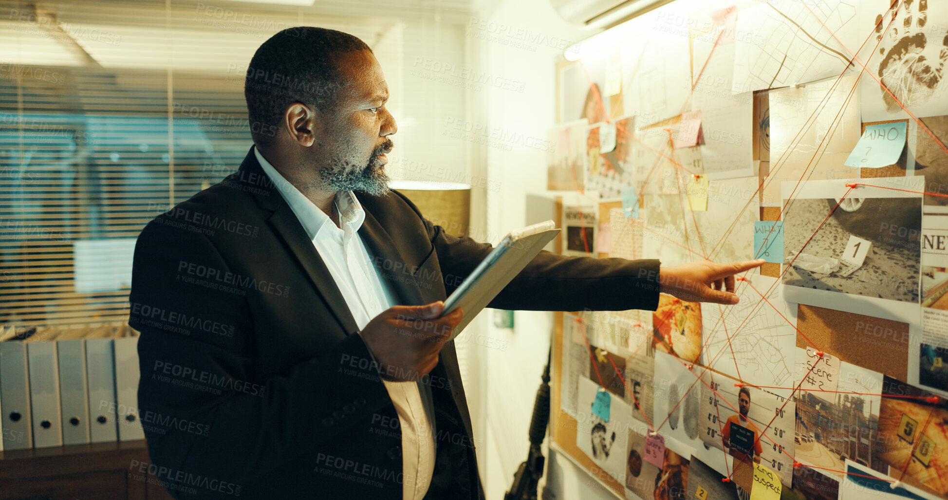 Buy stock photo Man, detective and tablet at board for case, pointing at evidence or documents with link for criminal investigation. Mature African policeman, tech and problem solving with crime analysis at night