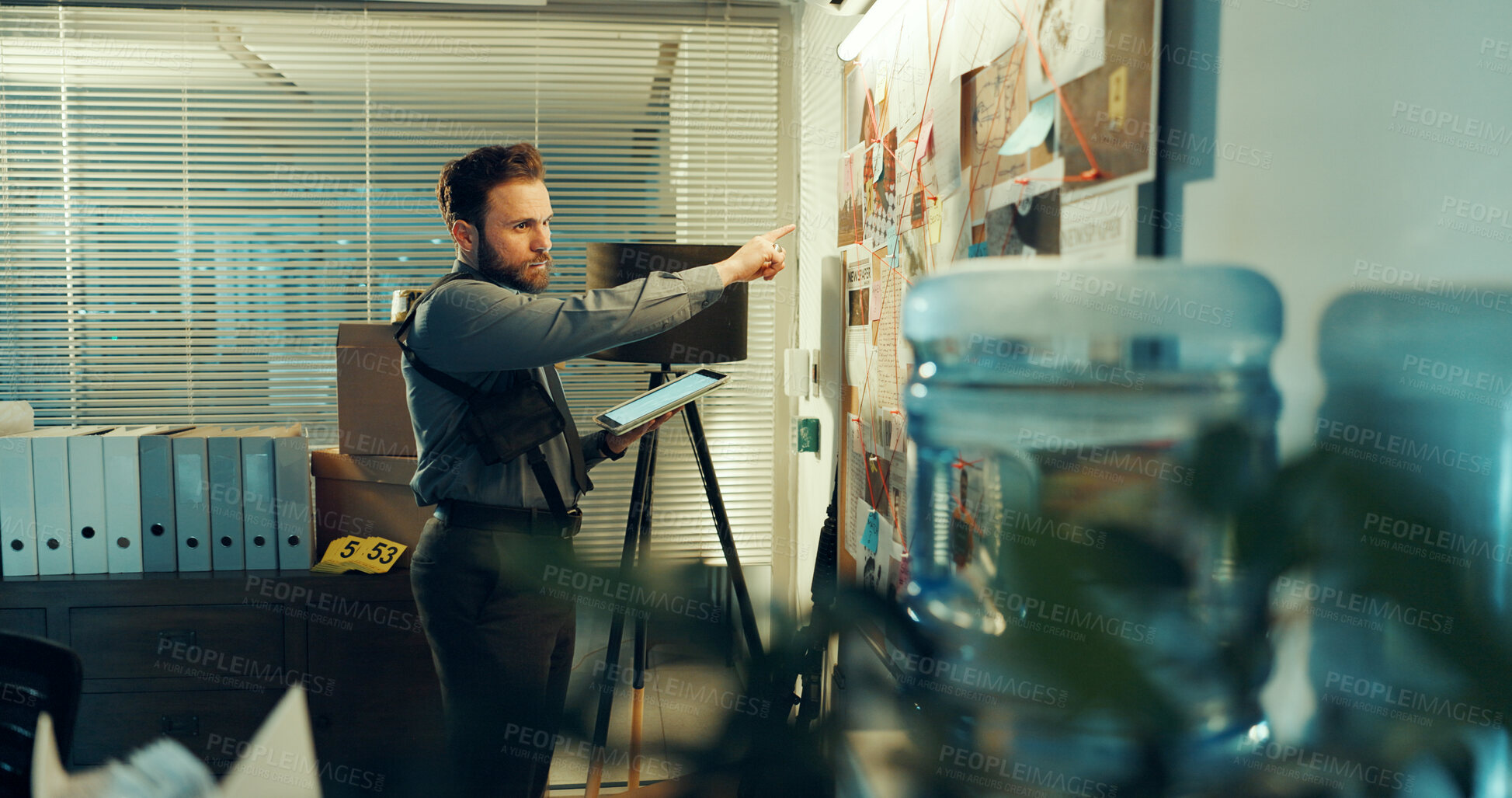 Buy stock photo Detective, man and board with evidence or case with tablet, investigation and criminal lead at police station. Investigator, problem solving and point at mindmap with tech, suspect and crime at night