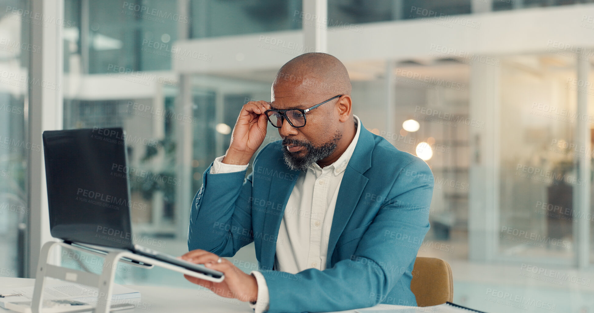 Buy stock photo Glasses, laptop and reading with business black man in office for company management or research. Computer, information and planning with mature manager at desk in workplace for administration report