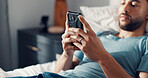 Hands, smartphone and man in bed for communication, social media or reading ebook on weekend at home. Male person, mobile app with text message or blog, email and contact with connectivity on day off