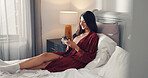 Phone, relax and smile with woman in bed of hotel room for accommodation, break or hospitality. App, communication and social media with happy guest in bedroom of lodge or resort for web browsing