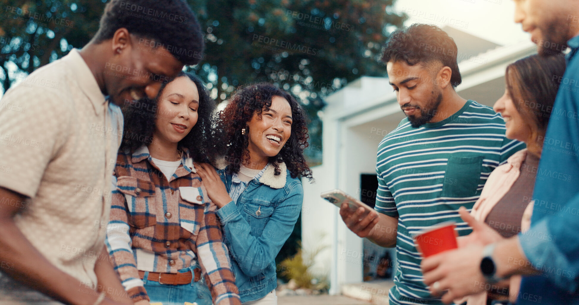 Buy stock photo Friends, happy and people at party in backyard with phone for bonding, relax and fun conversation. Hangout, weekend and men with women for celebration, social gathering and internet on smartphone