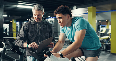 Buy stock photo Stationary bicycle, man and coach for fitness, help or workout timer for health in gym. Cycling, personal trainer and training on bike for spin class, challenge or check watch for exercise progress