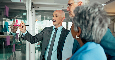 Buy stock photo Brainstorming, business people and writing on sticky note with team in office for financial schedule. Mature group, glass wall and discussion for strategy, investment ideas and agenda in meeting