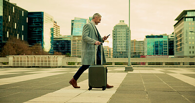 Buy stock photo Businessman, walking and phone with suitcase in city for travel, commute or career opportunity. Mature, man or traveler with luggage or mobile smartphone app for corporate business trip or schedule