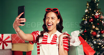 Buy stock photo Winking, woman and shopping for Christmas, selfie and memory of festive celebration and photography. Studio, person and social media post of Xmas gifts, green background or profile picture on holiday