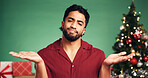 Christmas, hands and confused with portrait of man in studio for decision, wish list and holiday season. Option, festive gift idea and xmas offer with person on green background for mockup space