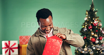 Buy stock photo Black man, Christmas in studio and happy for gift, opening box and holiday with festive season on green background. Celebration, bokeh and person with smile for present, tradition or xmas package