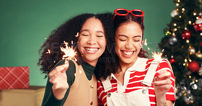 Buy stock photo Women, sparkler and smile in Christmas studio with friends, holiday and festive cheer for bonding. Hug, love and firework by tree for xmas celebration, presents or decoration on green background