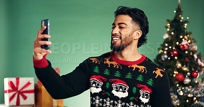 Buy stock photo Christmas, happy and man with selfie in studio for festive, tradition or holiday celebration. Smile, phone and person with photography picture for memory by xmas tree and gifts on green background.