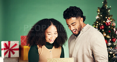Buy stock photo Christmas, gift and surprise with couple in studio for holiday season, celebration and xmas package. Present, festive tradition and man and woman with box on green background for light and wow