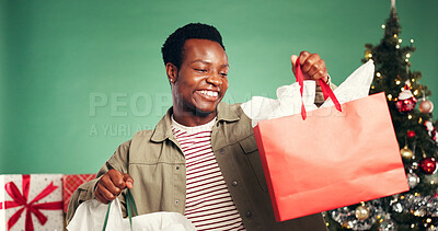 Buy stock photo Smile, black man and bag in studio for Christmas celebration, gift giving and xmas discount. Happy, male person and festive with package choice, holiday giveaway and offer present on green background