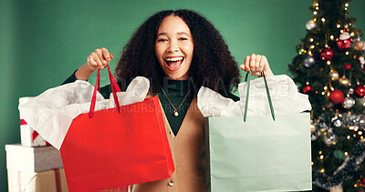 Buy stock photo Portrait, woman and bags in studio for Christmas celebration, gift giving and xmas discount. Excited, person and festive with shopping package, holiday giveaway and offer present on green background