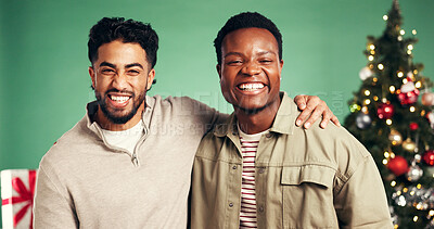 Buy stock photo Christmas, portrait and happy friends hug in studio for holiday, festive season or laughing. Xmas, embrace and men smile for celebration with tree decoration, present or support on green background