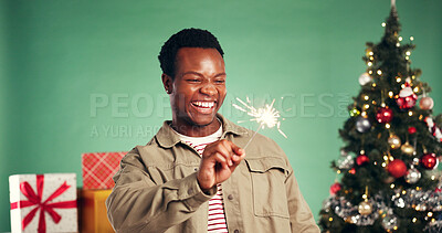Buy stock photo Christmas, laugh and black man with sparkler in studio for festive season on green background. African person, xmas and firework for holiday celebration, funny and excited for party with present