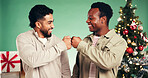 Christmas, fist bump and friends in studio for celebration, support and holiday season. Happiness, festive event and xmas vacation with excited people on green background for December party together