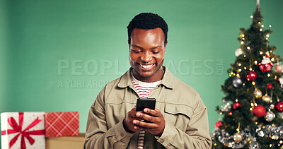 Buy stock photo Christmas, smile and black man with phone in studio for holiday, festive season or gift shopping. Xmas, mobile and happy person with app to purchase present online with space on green background