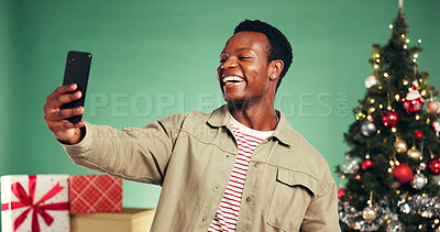 Buy stock photo Christmas, happy and black man with selfie in studio for festive, tradition or holiday celebration. Smile, excited or African person with photography picture by xmas tree or gifts by green background