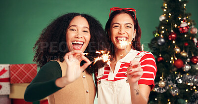 Buy stock photo Women, sparkler and portrait in Christmas studio with friends, holiday and festive cheer for bonding. Hug, love and firework by tree for xmas celebration, presents or decoration on green background