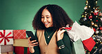 Shopping bag, Christmas and woman with smartphone, studio or discount for presents on festive season. Ecommerce, purchase and person with gifts for Xmas, green background and browsing on mobile app