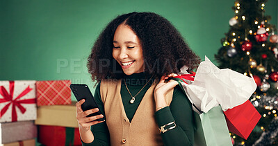 Buy stock photo Shopping bag, Christmas and woman with smartphone, studio or discount for presents on festive season. Ecommerce, purchase and person with gifts for Xmas, green background and browsing on mobile app