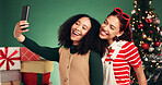 Women, friends and selfie for Christmas, studio and memory of December holiday, bonding and festive. Green background, people and excited on Xmas season, happy or profile picture on social media post