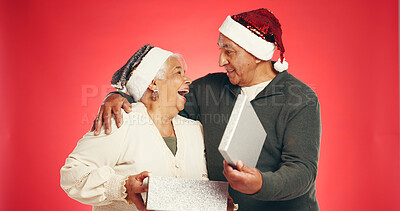 Buy stock photo Gift box, christmas and senior couple in studio with festive, holiday or marriage tradition. Excited, happy and elderly man with woman for opening present in xmas season together by red background.