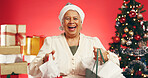 Shopping bags, Christmas and portrait of old woman in studio for holiday season, celebration or xmas sale. Festive tradition, retail deal and December vacation with senior person on red background