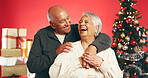 Hug, laugh and senior couple with christmas in studio with love, festive and marriage tradition. Happy, retirement and elderly man embracing woman by xmas tree for celebration by red background.