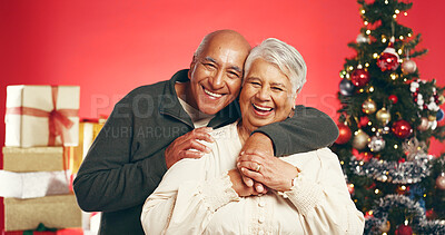 Buy stock photo Happy, christmas and portrait of senior couple in studio with love, festive and marriage tradition. Hug, retirement and elderly man embracing woman by xmas tree for celebration by red background.