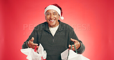 Buy stock photo Christmas, portrait or old man with shopping in studio for holiday discount, gifts or tradition. Mockup space, senior person or happy with bags on red background for xmas sale, festive or celebration
