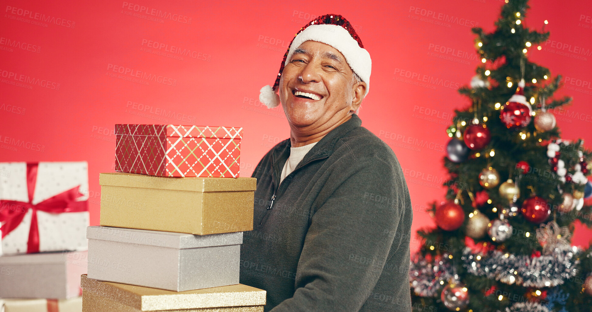 Buy stock photo Gift boxes, christmas and senior man in studio for tradition, festive or holiday celebration. Portrait, santa hat and elderly person with presents for xmas season with decorations by red background.