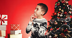 Thinking, child and boy with presents, Christmas or celebration for festive event or red background. Studio, reflection and excited for December holiday, gifts and decorations for Xmas and season