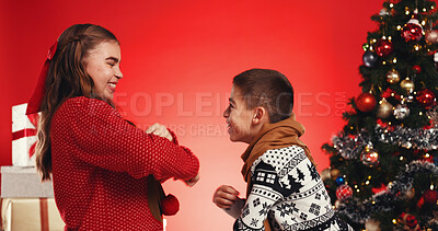Buy stock photo Siblings, girl and boy with Christmas tree in studio, dancing or family with gift on red background. Children, brother and sister with xmas jersey, smile or laugh with celebration for festive holiday