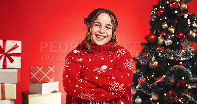 Buy stock photo Christmas, portrait and child with arms crossed, studio and smile for celebration or festive season. Red background, girl and excited with Xmas sweater, presents and tree with ornaments in USA