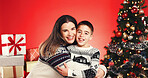 Christmas, portrait and people hug with child for love and holiday celebration. Happy woman, son and embrace for xmas event with smile, festive season and family with support on red studio background