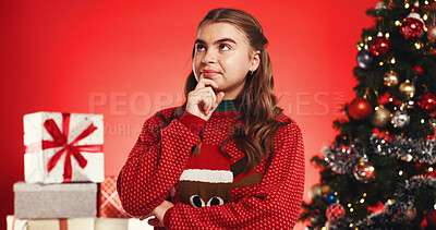 Buy stock photo Girl, thinking and Christmas tree in studio for gift, wish and festive sweater on red background. Teenager, reflection and perspective with xmas jersey, decoration and boxes with guess for present