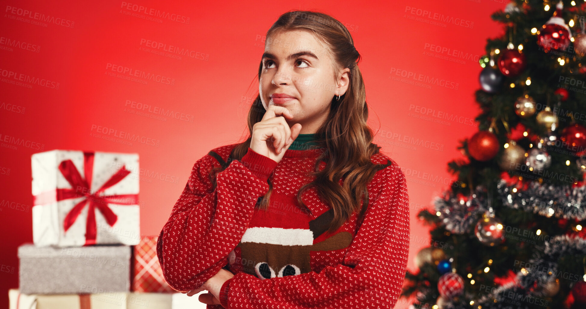 Buy stock photo Girl, thinking and Christmas tree in studio for gift, wish and festive sweater on red background. Teenager, reflection and perspective with xmas jersey, decoration and boxes with guess for present