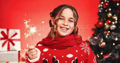 Buy stock photo Portrait, Christmas and child with sparkler, studio and excited for celebration or December holiday. Red background, festive season and girl with Xmas sweater, presents and tree with ornaments in USA