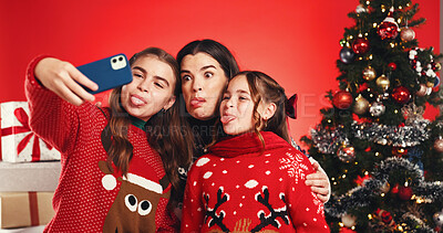 Buy stock photo Christmas, mother and children with selfie in studio for festive season, tongue out or bonding. Goofy family, people and photography on red background for winter holiday, xmas memory and celebration