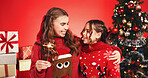 Happy, sisters and children with sparkler, Christmas and bonding on festive season, hug and holiday. Studio, teenager and embrace with girl, family and love on Xmas, red background or decorations