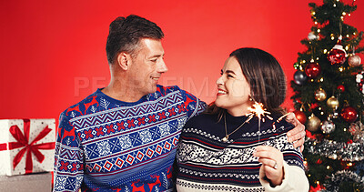Buy stock photo Christmas, hug and sparkler with couple in studio together for bonding and gift or present. Firework, celebration and love with mature man and woman on red background for festive tradition or holiday