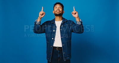 Buy stock photo Promotion, pointing up and man in studio with launch, announcement and offer on blue background. Model, space and person with hand gesture, opinion and opportunity with decision or choice for deal