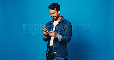 Buy stock photo Reading, phone and search with man in studio for social media, communication and blog post. Online news feed, text message and networking chat with person on blue background for mockup space and app