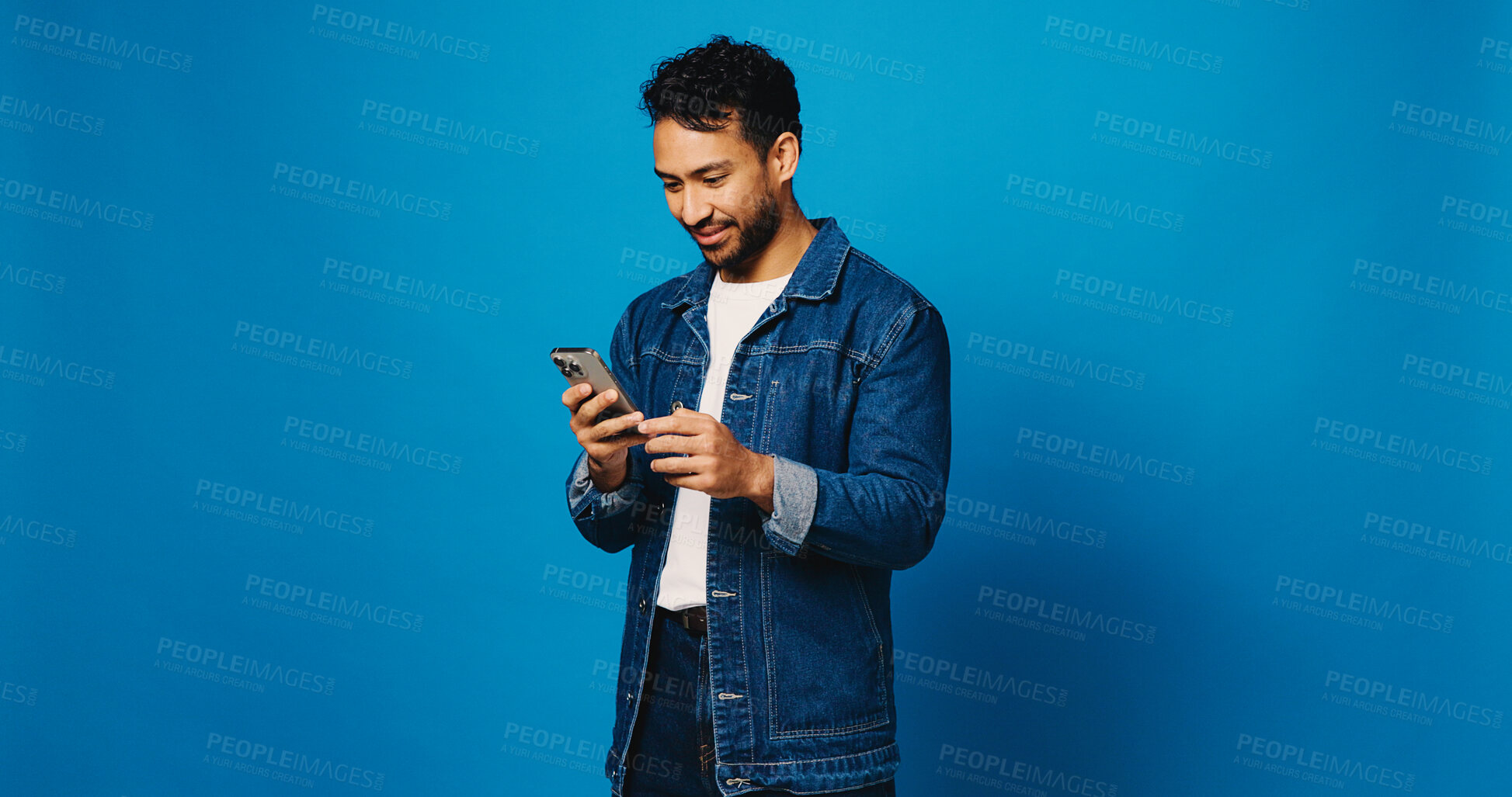 Buy stock photo Reading, phone and search with man in studio for social media, communication and blog post. Online news feed, text message and networking chat with person on blue background for mockup space and app