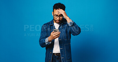 Buy stock photo Phone, confused and stress with man in studio for crypto scam, account phishing or fintech loss. Fake nft token, anxiety and password error with person on blue background for mockup space and hacking