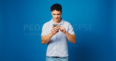 Buy stock photo Phone, smile and scroll with man in studio for connection, text message and social media. Online news, search and mockup space with person on blue background for post update, typing and network
