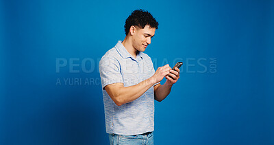 Buy stock photo Phone, reading and scroll with man in studio for social media, networking and connection. Mockup space, text message and search with person on blue background for contact, typing or communication app
